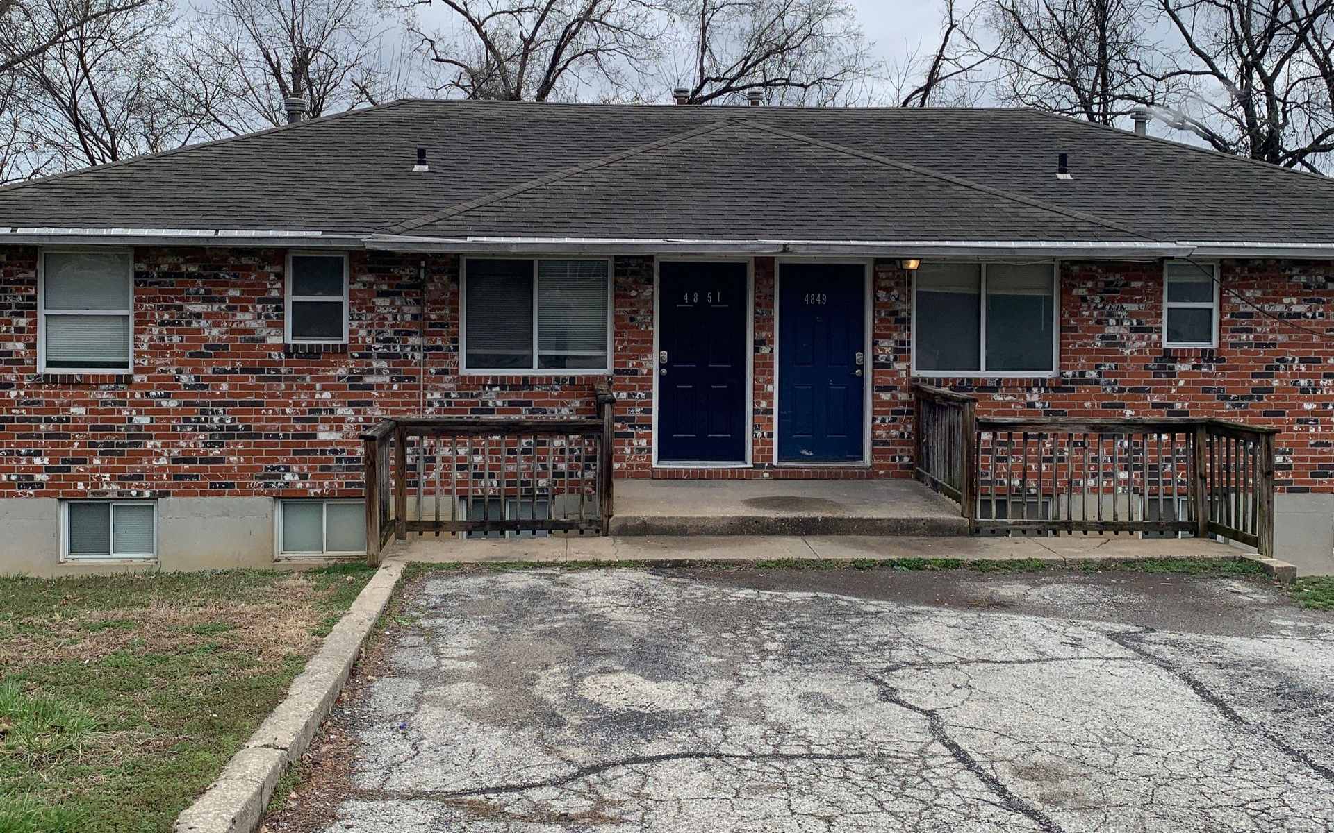 Brick apartment building with burgundy doors and windows. Stairs lead to the entries.