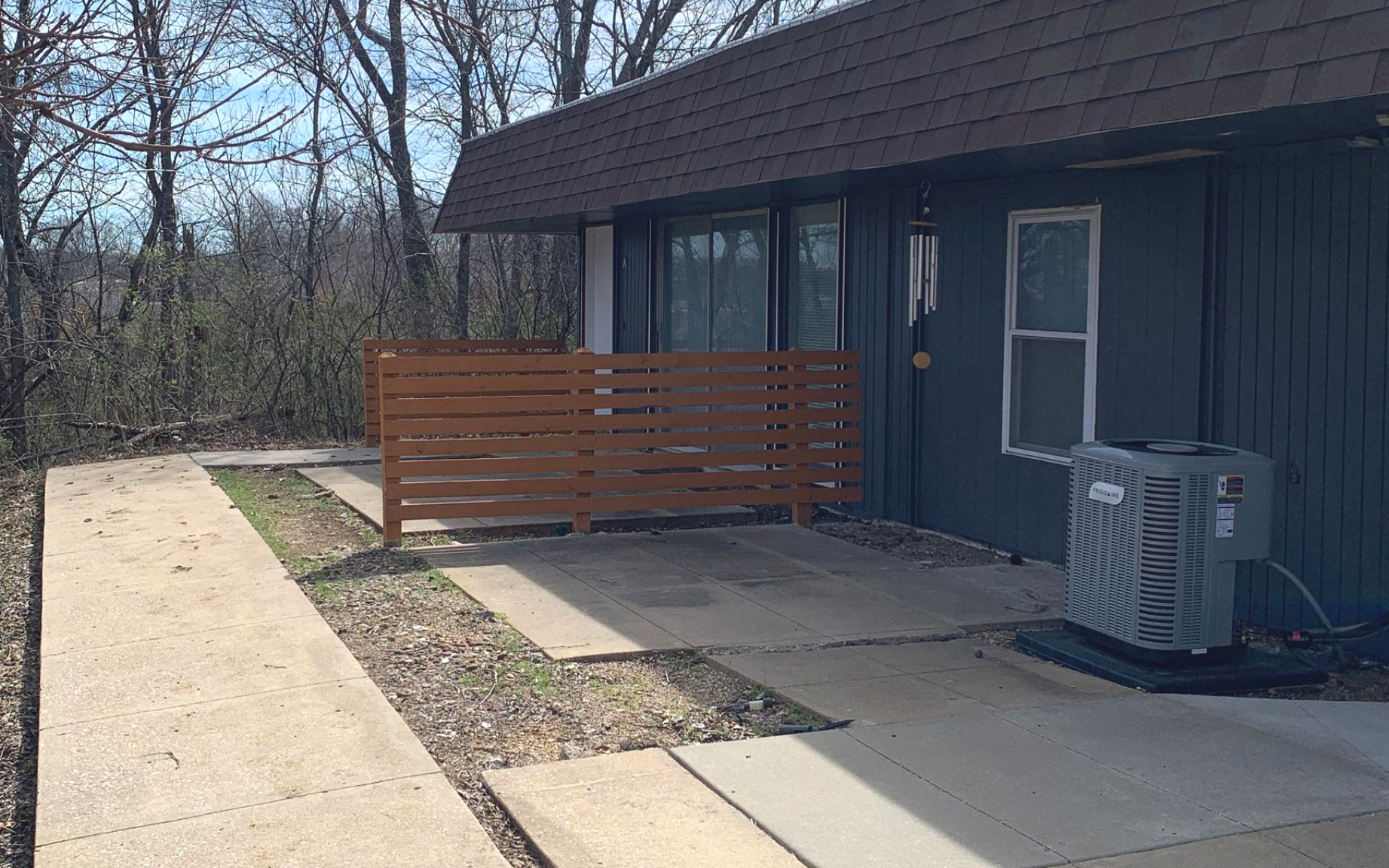 Row of gray townhouses with brown roofs and wooden fences.