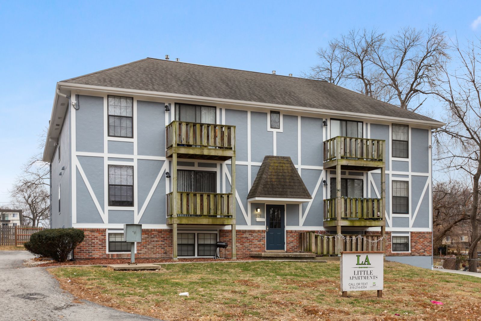 Two-story apartment building with light blue siding, white trim, and small wooden balconies.