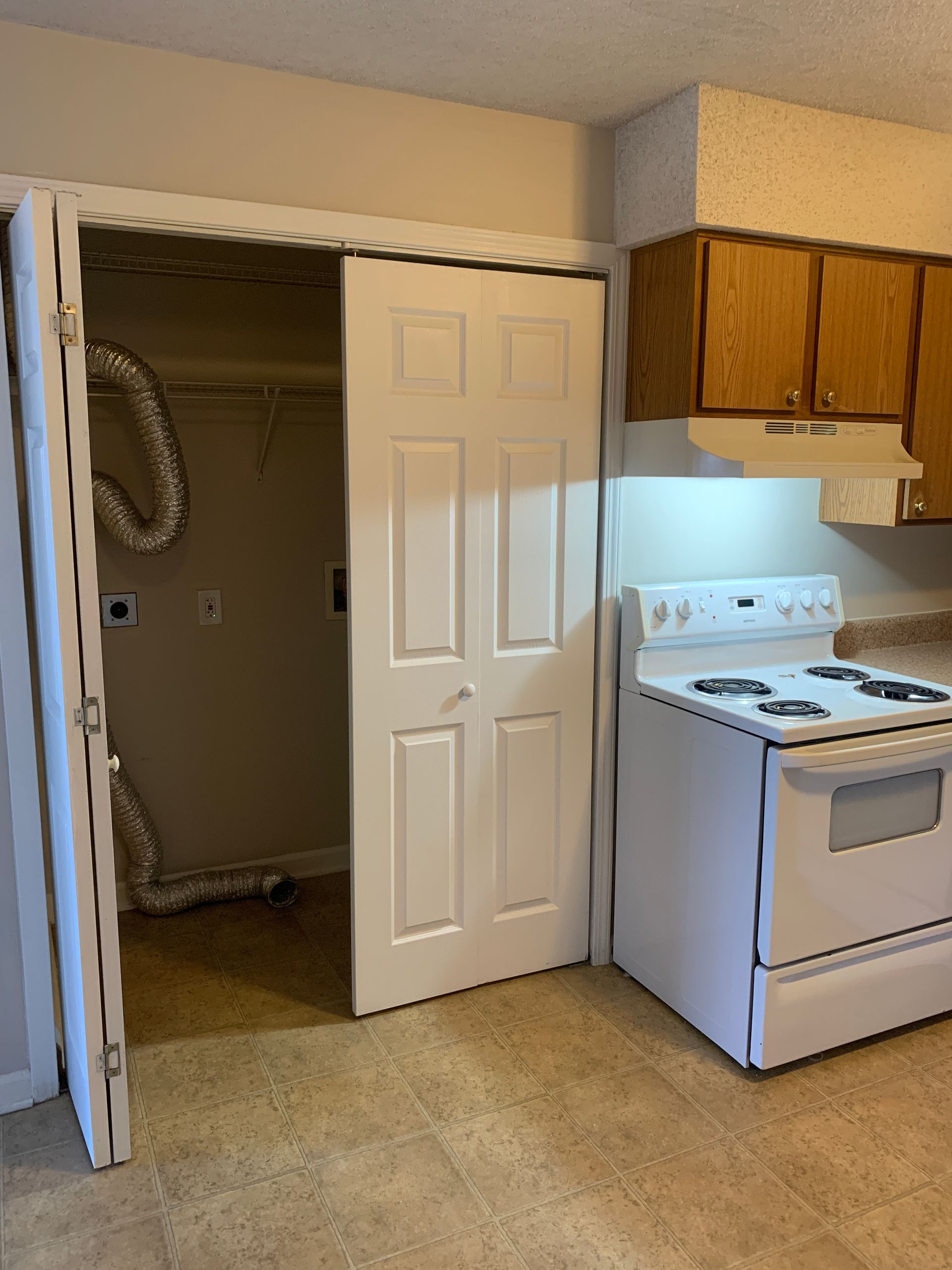 Kitchen with a white stove, cabinets, and a laundry closet with open doors.