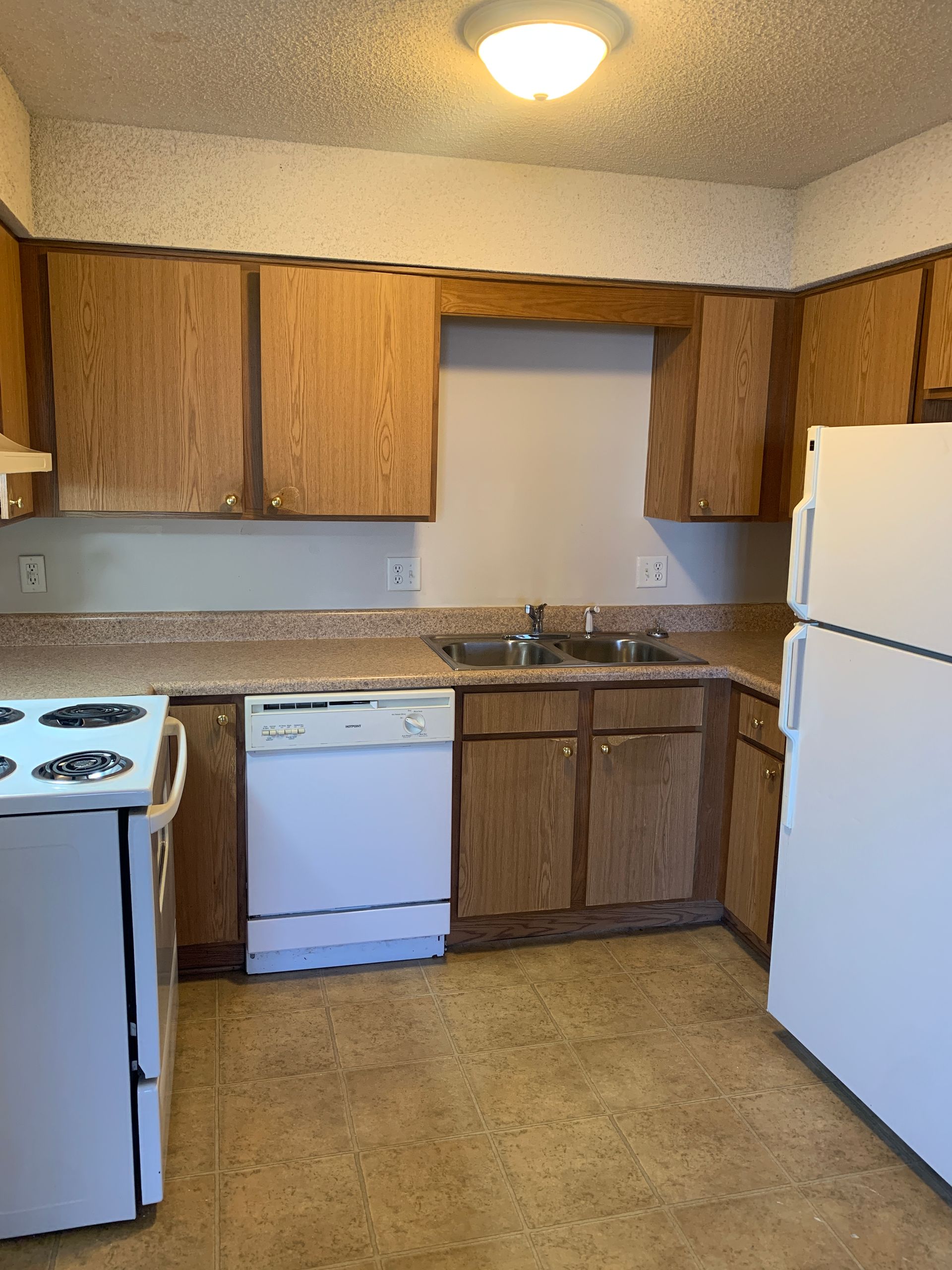 Kitchen with light-colored cabinets, white appliances, and a tan floor.