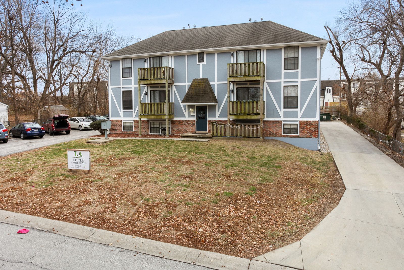 Apartment building with blue siding, two balconies, and a grassy yard.