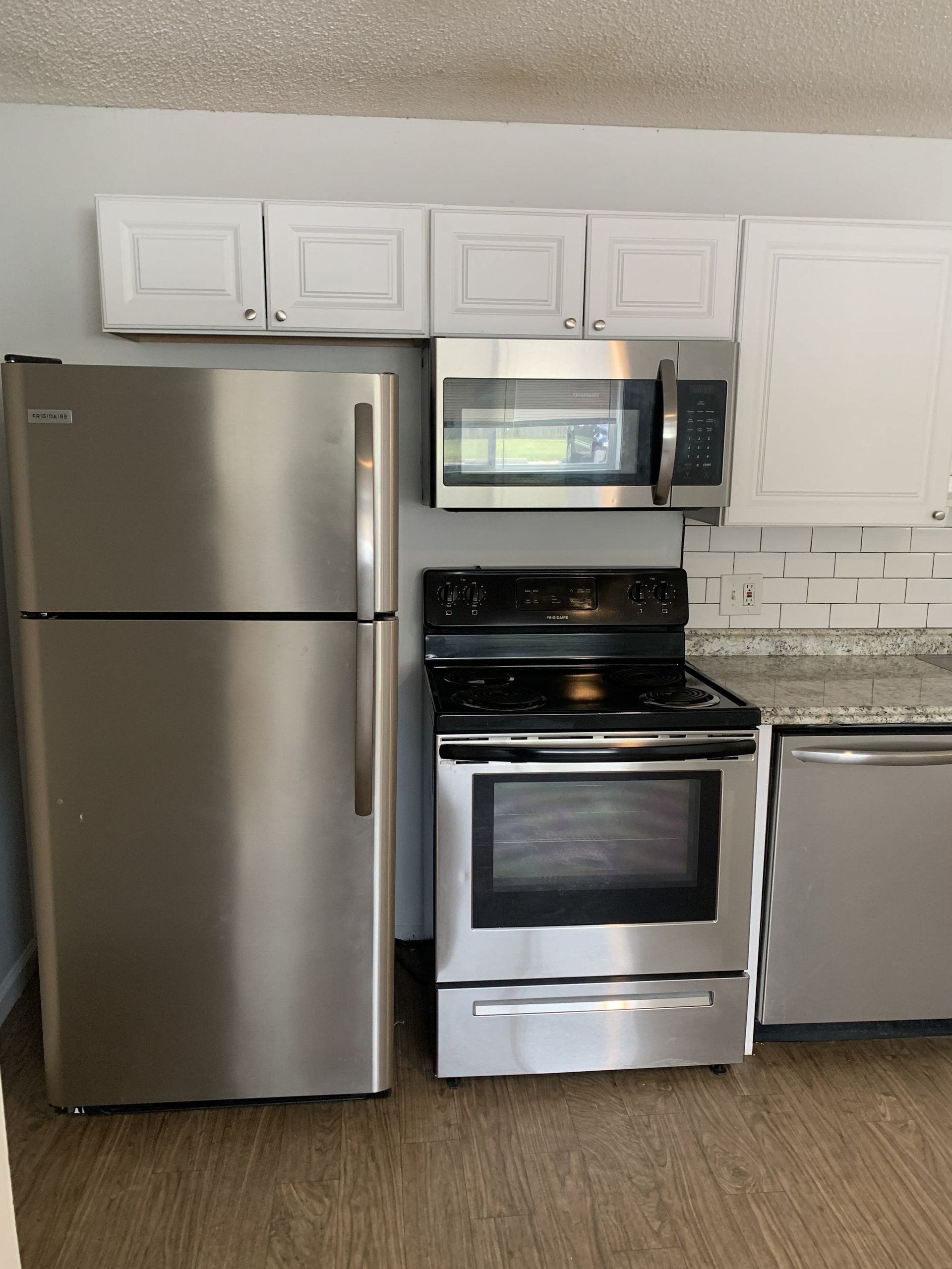 Stainless steel kitchen appliances, refrigerator, stove, microwave, and cabinets.