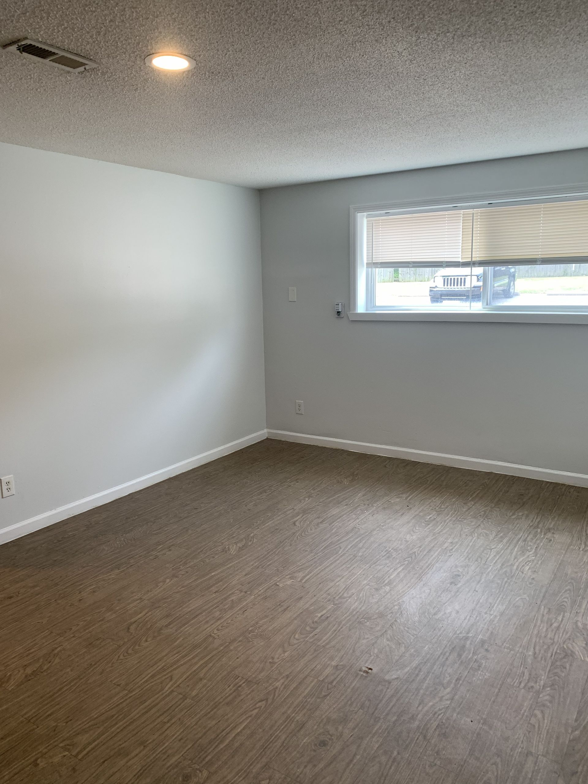 Empty room with white walls, carpet, and a window with blinds.