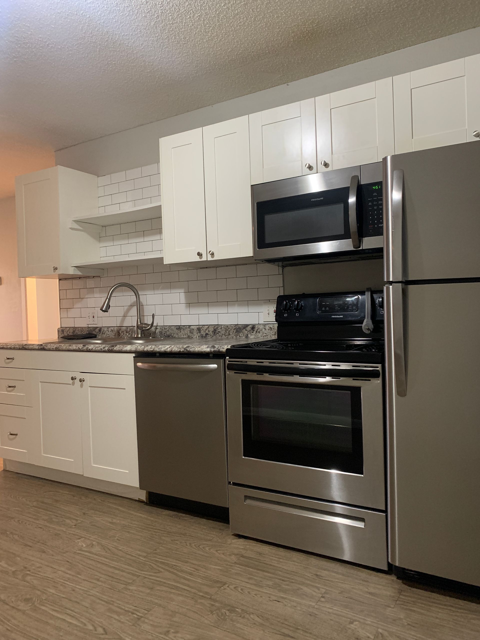 Kitchen with white cabinets, stainless steel appliances, and gray countertops.