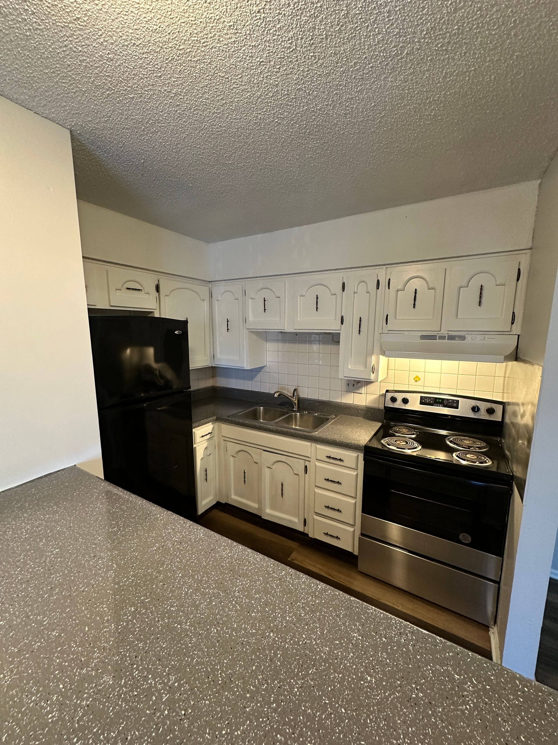 Kitchen with white cabinets, black appliances, and a stainless steel stove.