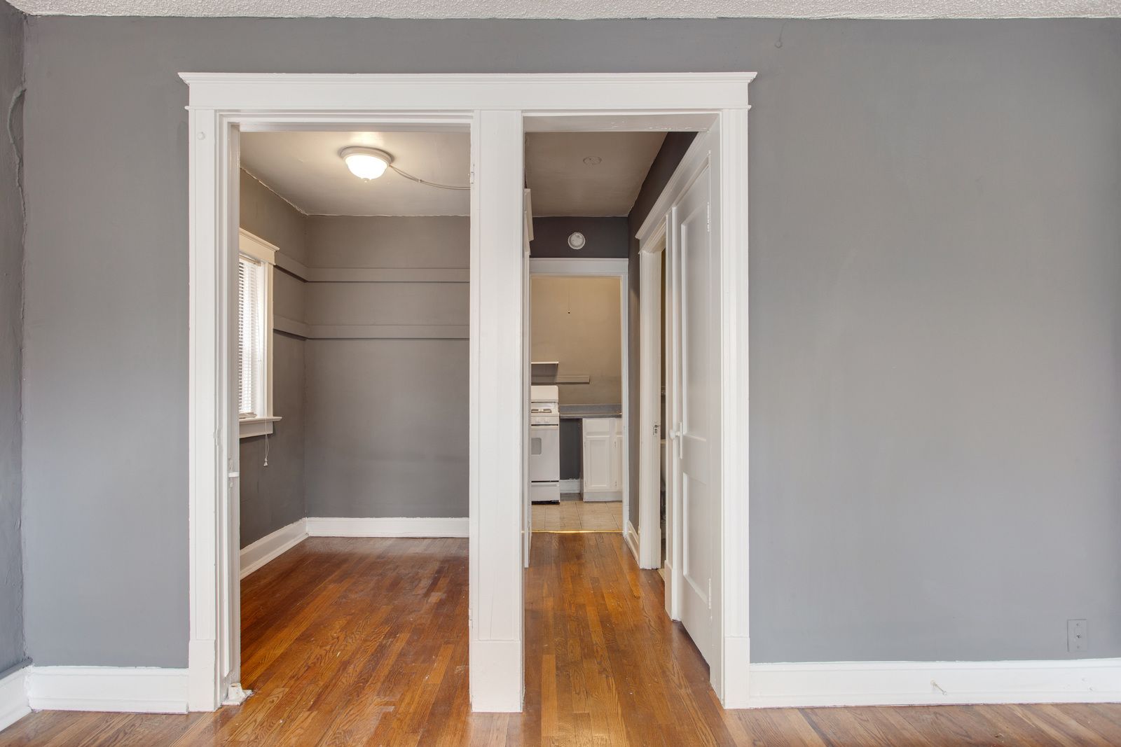 Gray room with doorways to other rooms, hardwood floors.