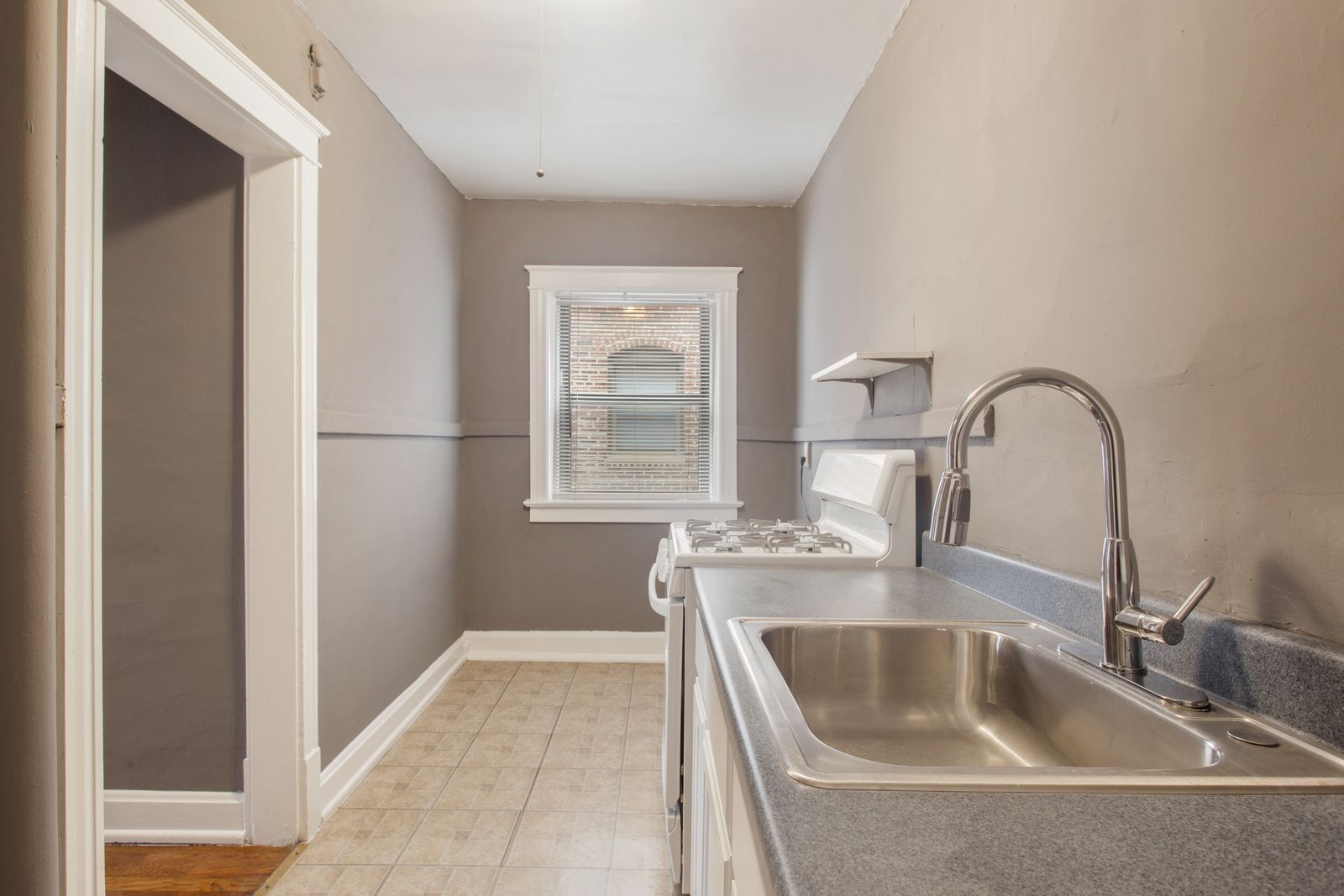 Laundry room with sink, washer, window, and neutral-colored walls and floor.