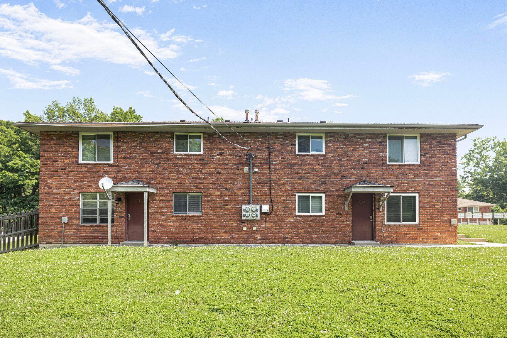 Red brick duplex with green lawn and blue sky.