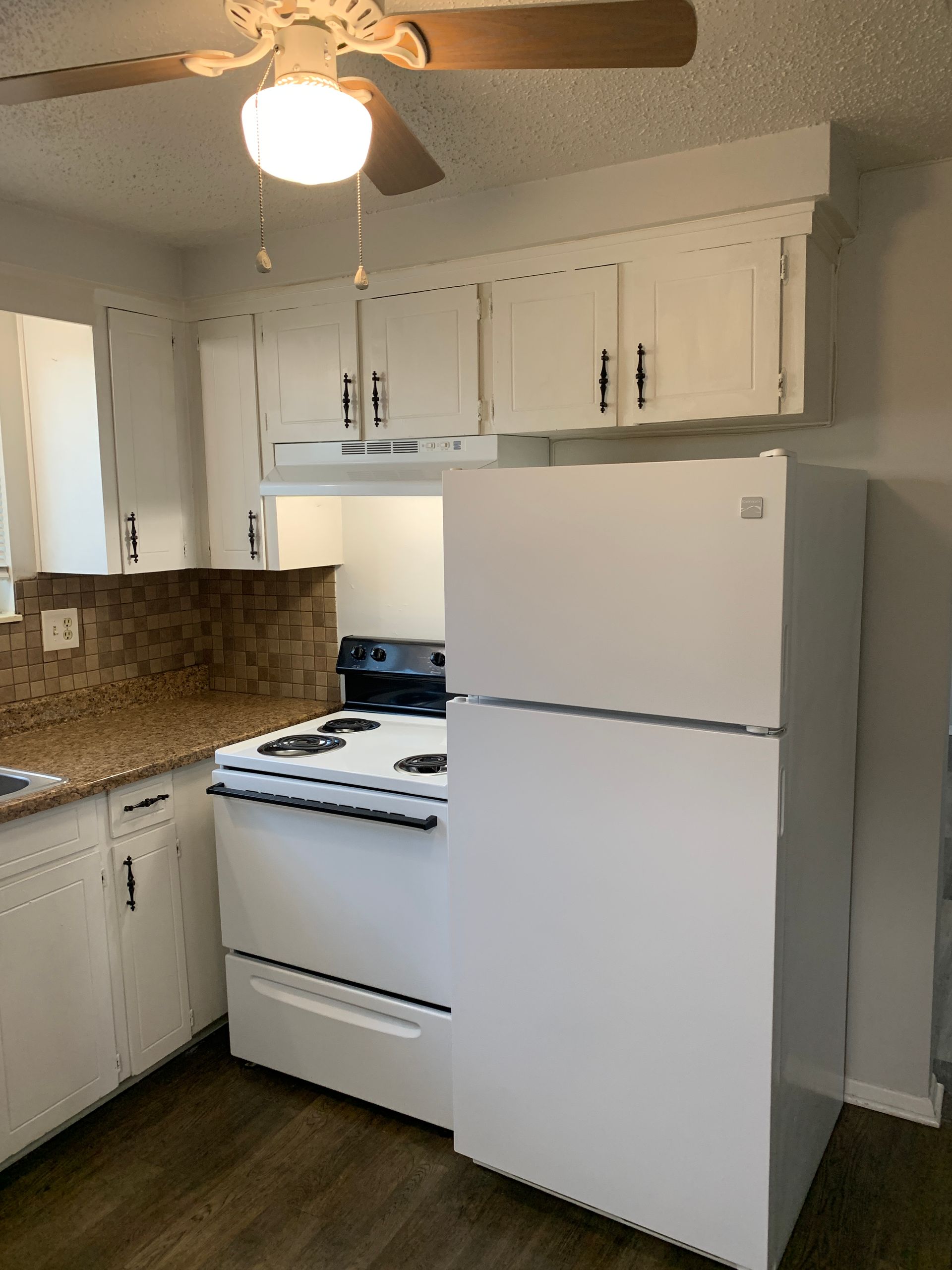 Kitchen with white cabinets, appliances, and a brown countertop, and a ceiling fan.