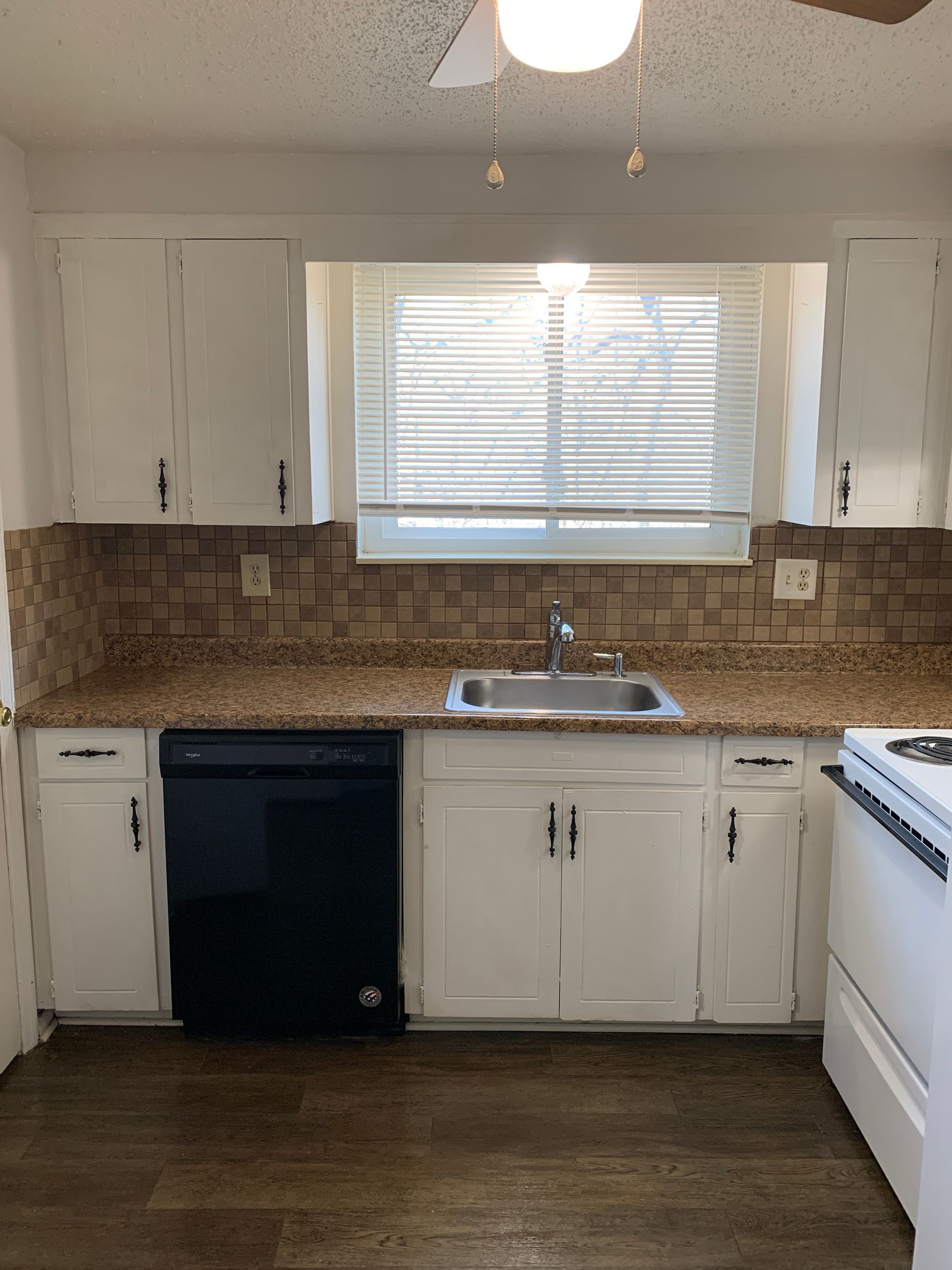 Kitchen with white cabinets, a black dishwasher, and a window above the sink.