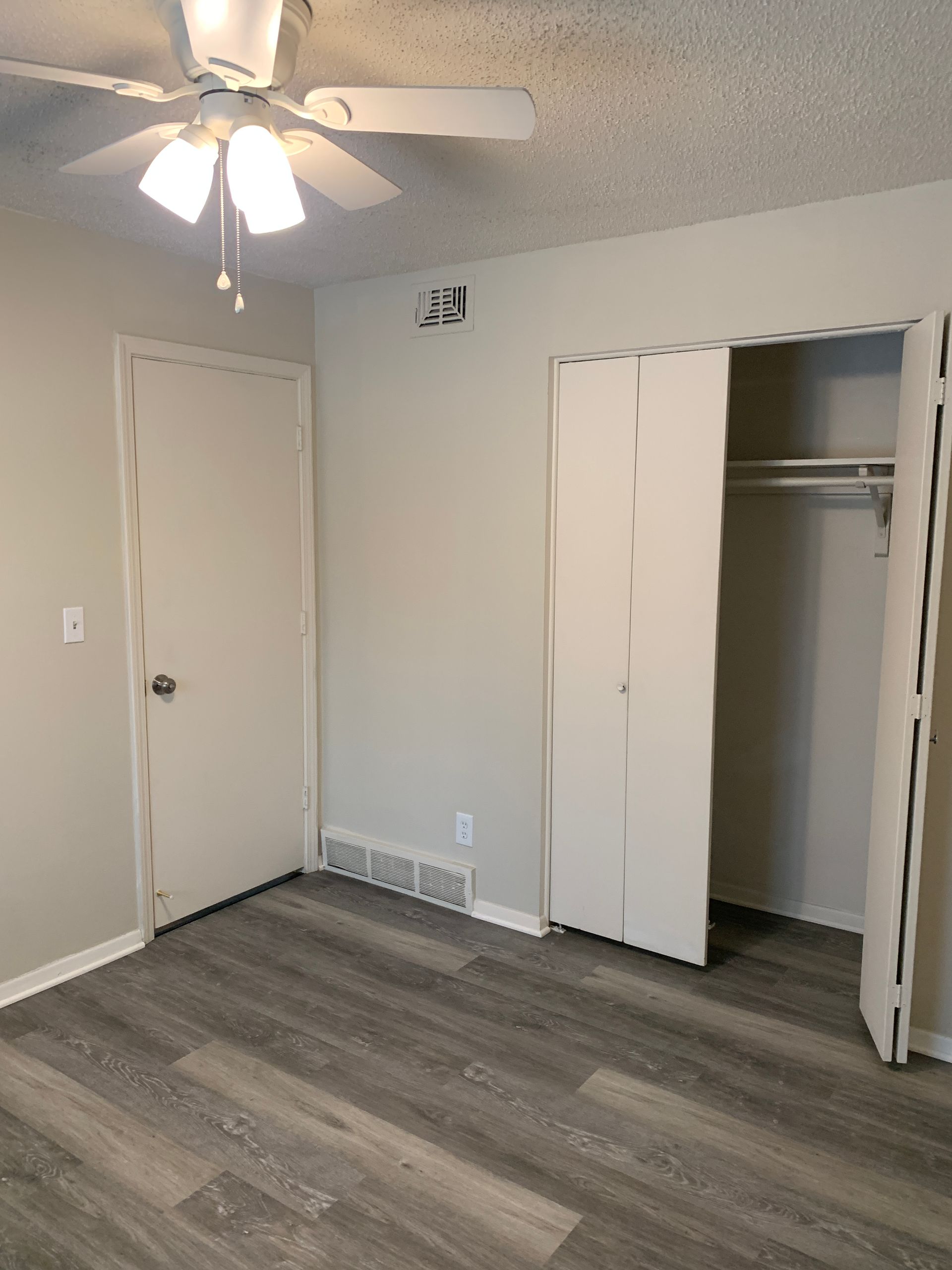 Bedroom interior with a closet, door, ceiling fan, and gray flooring.