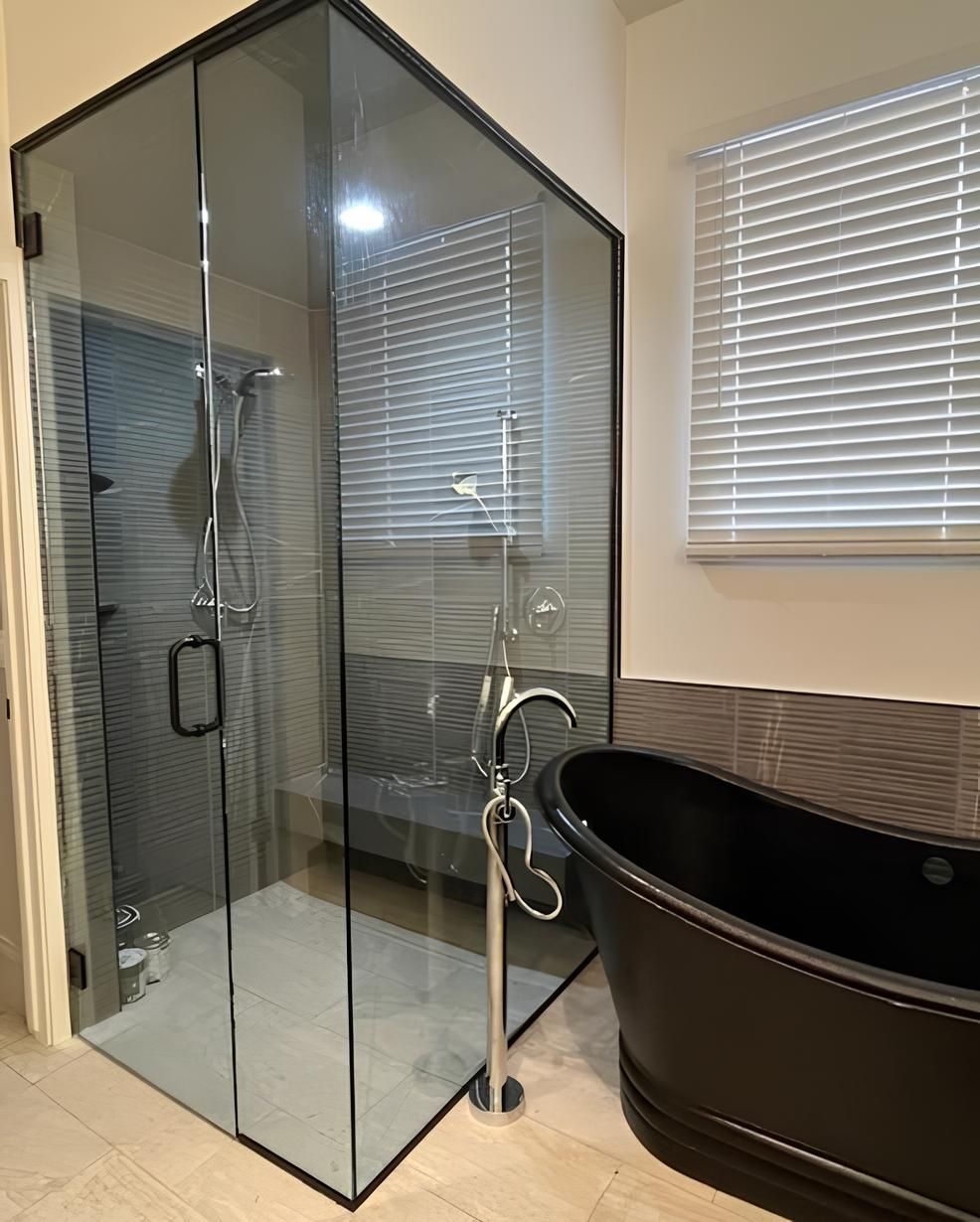 A bathroom with a black bathtub and a glass shower stall.