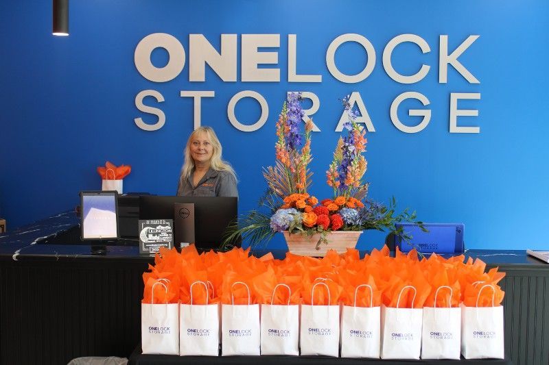 A woman sitting at a desk in front of a sign that says onelock storage