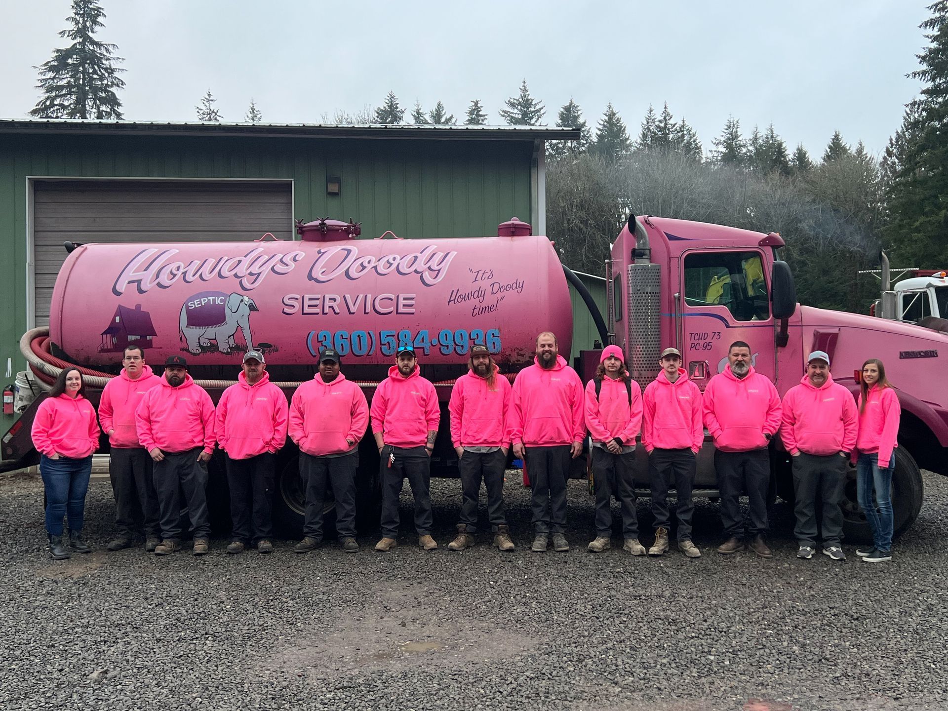 Group of people in pink hoodies posing with a pink septic service truck.