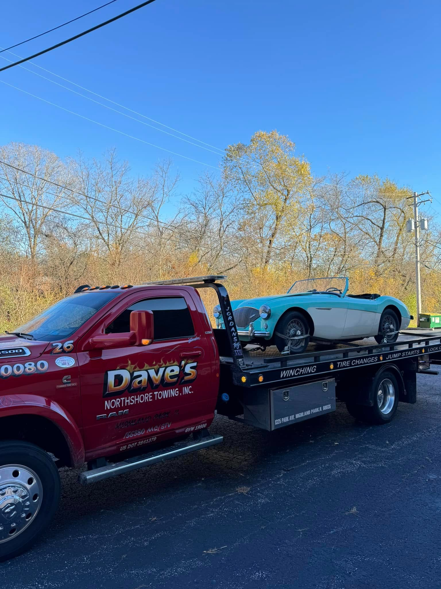 A red tow truck is towing a blue sports car.