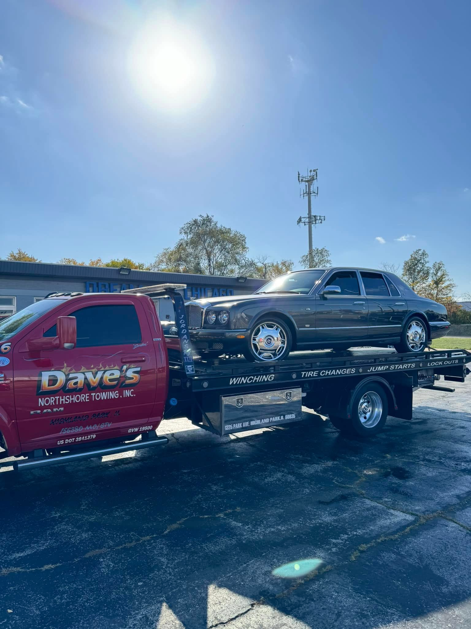 A tow truck is carrying a car on the back of it.