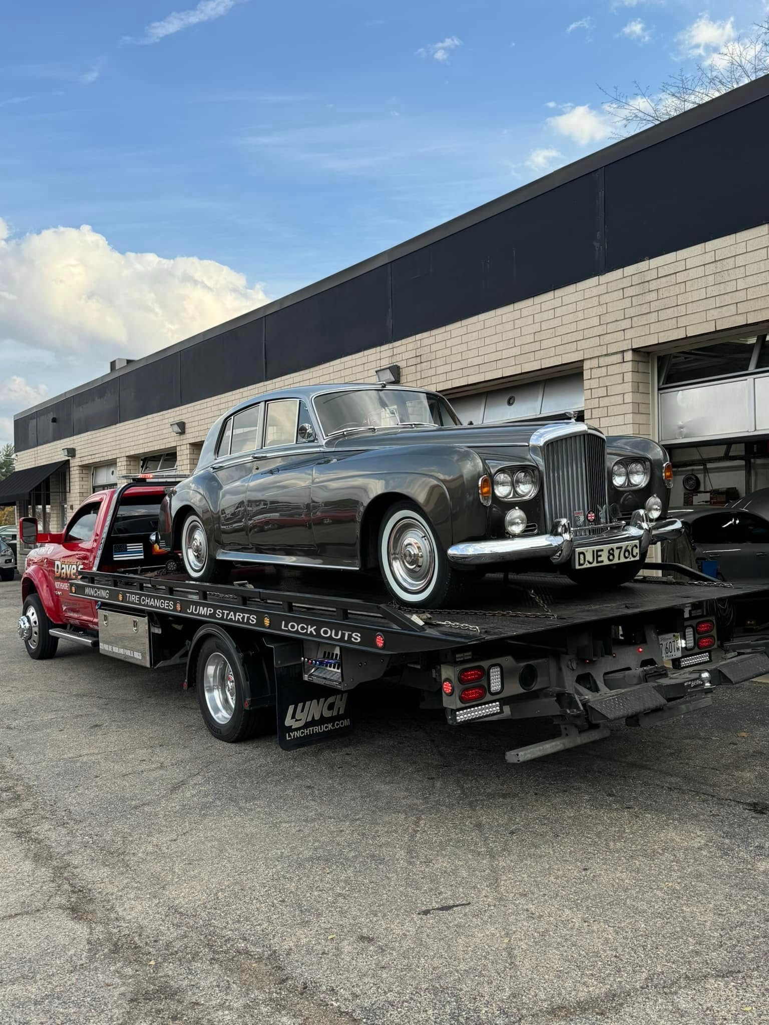 An old car is being towed by a tow truck.