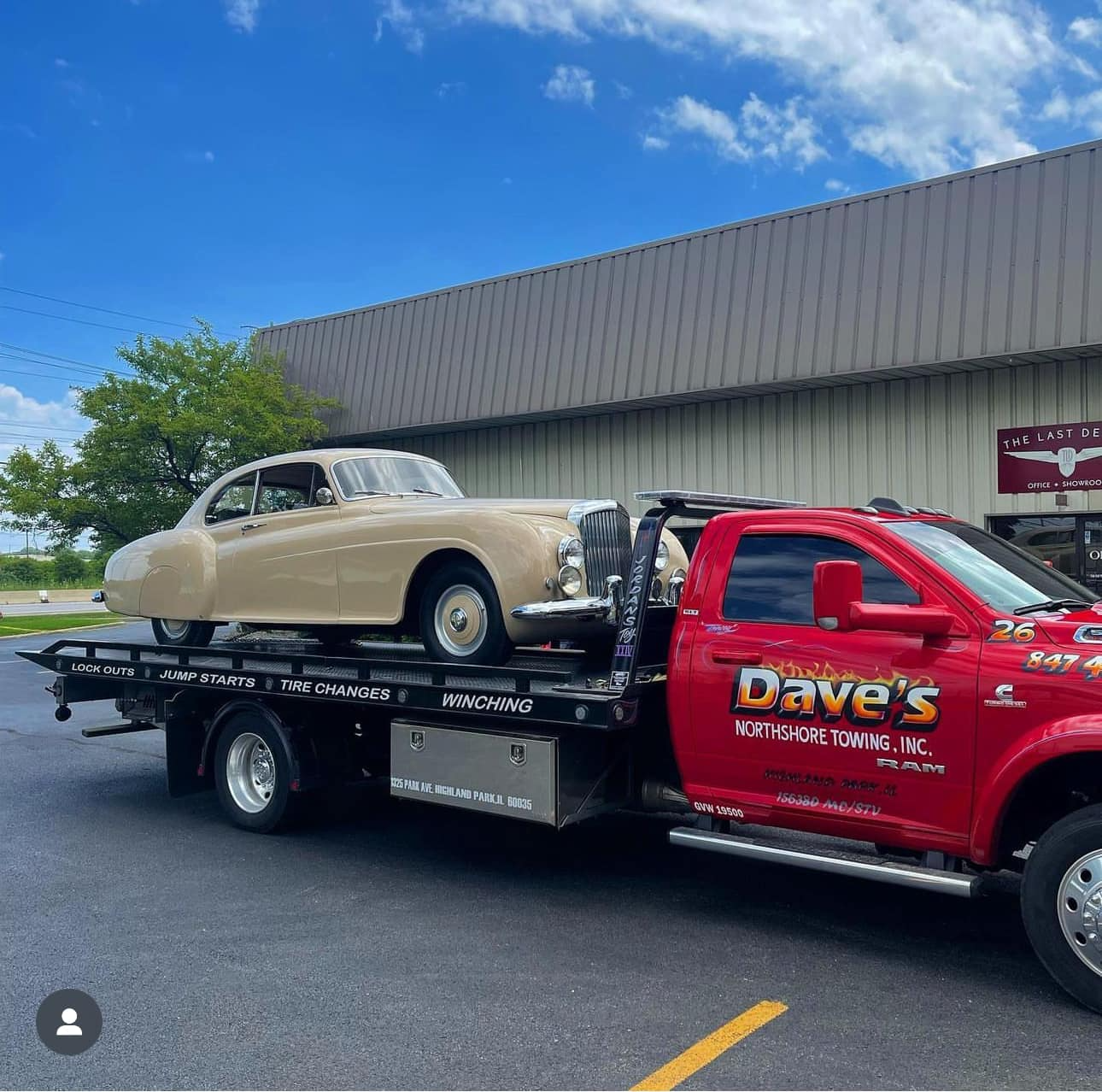 An old car is being towed by a tow truck.