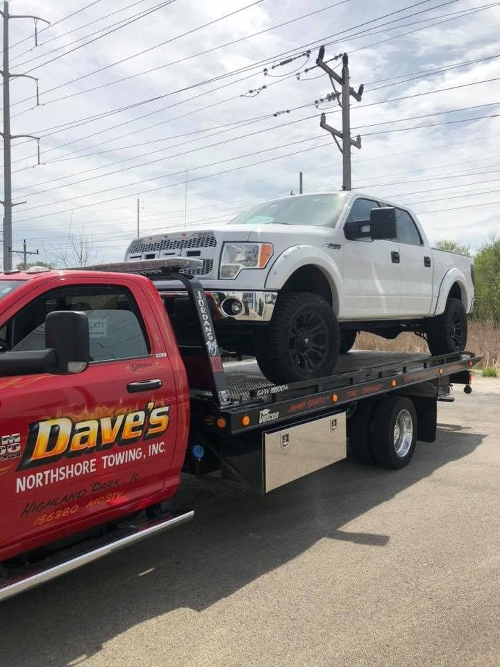 A white truck is sitting on top of a tow truck.