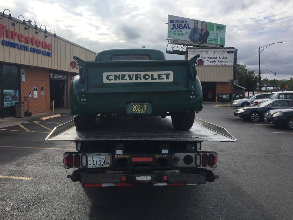 A green chevrolet truck is being towed by a tow truck