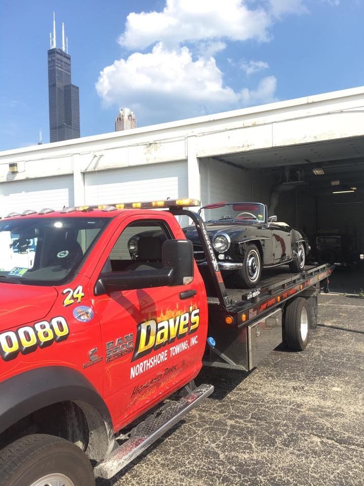 A red tow truck is carrying a jeep on the back of it.
