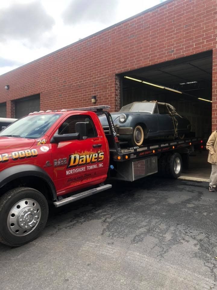A red tow truck with a car on the back is parked in front of a brick building.