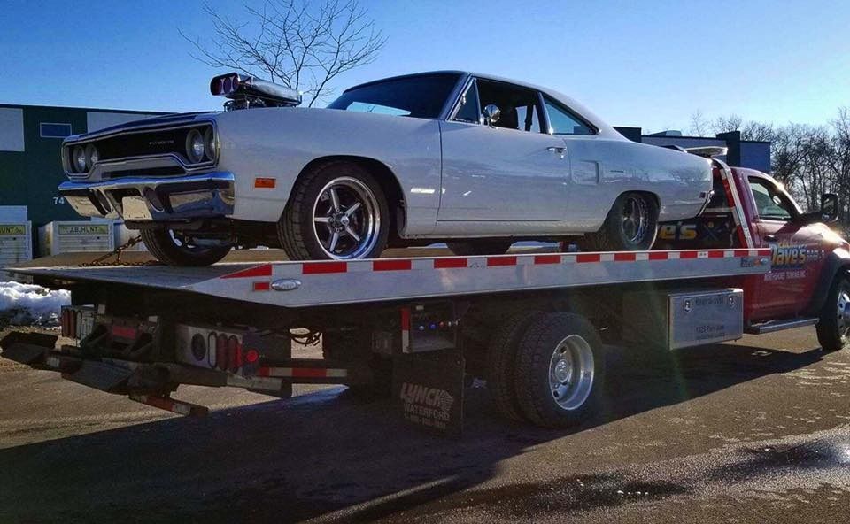 A white car is sitting on top of a tow truck.
