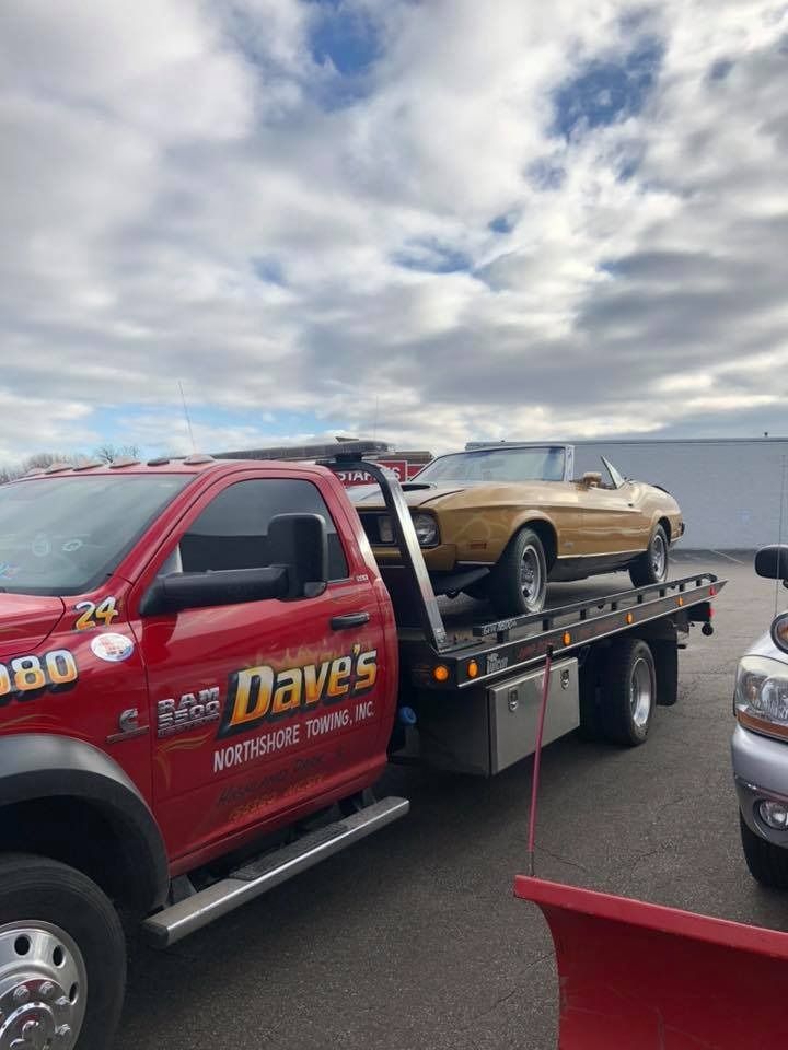 A red tow truck is towing a yellow car.