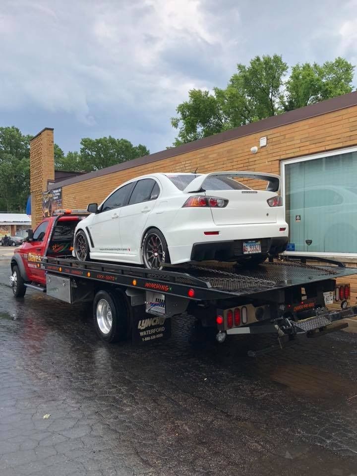 A white car is being towed by a tow truck.