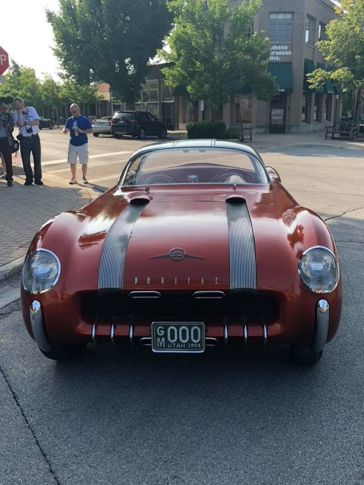 A red sports car with a license plate that says hood