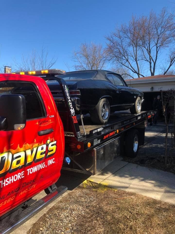 A black car is being towed by a red tow truck.
