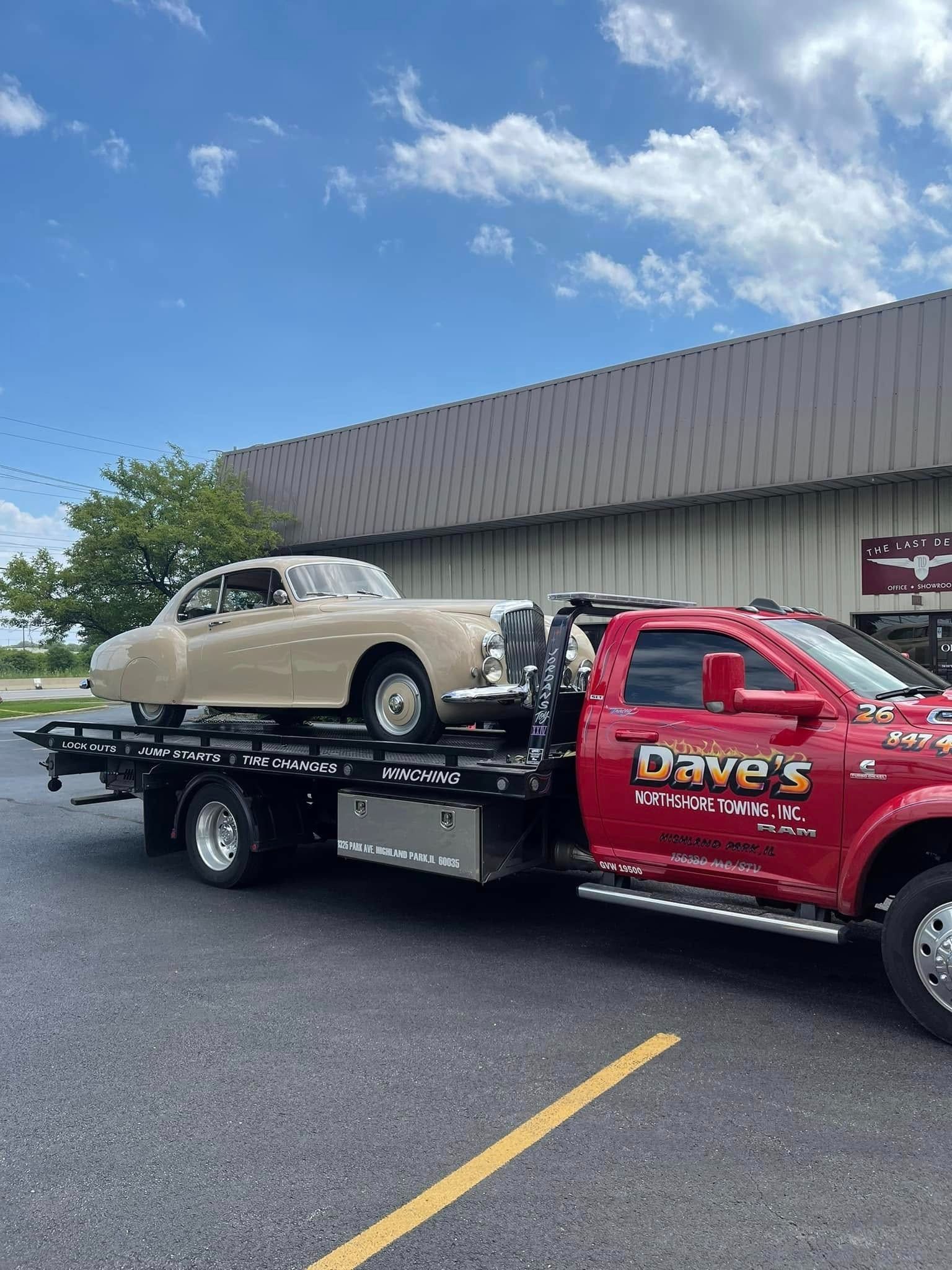 A tow truck is carrying a car on the back of it.