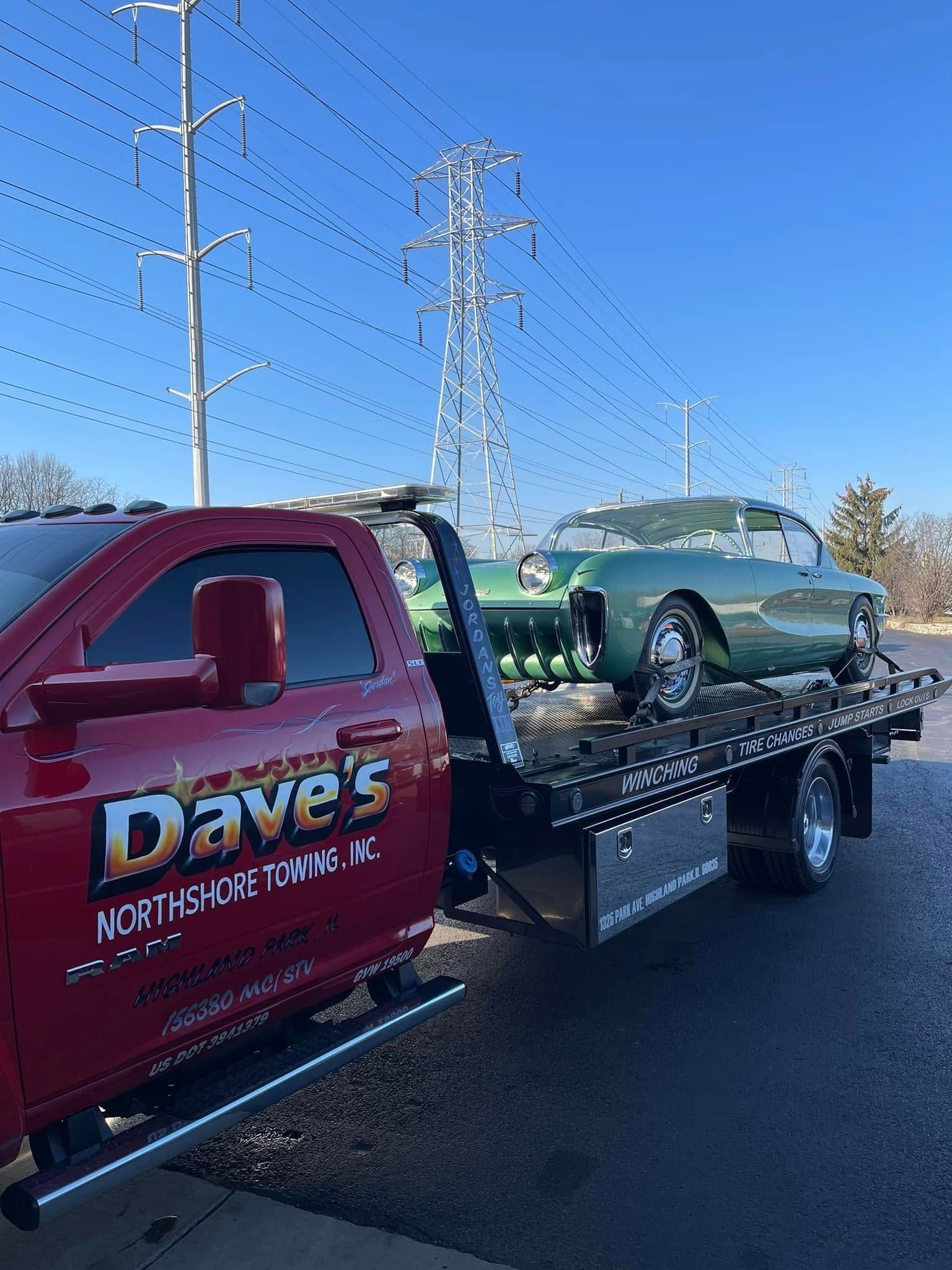 A red tow truck is towing a green car.