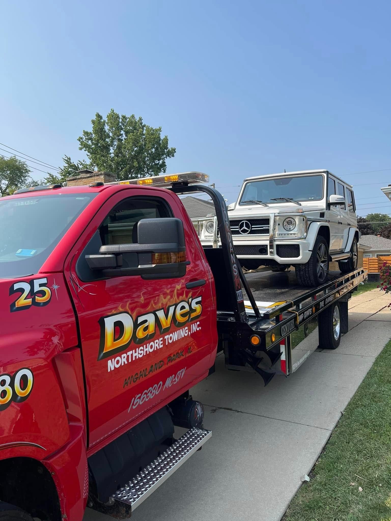 A red tow truck is towing a white jeep.