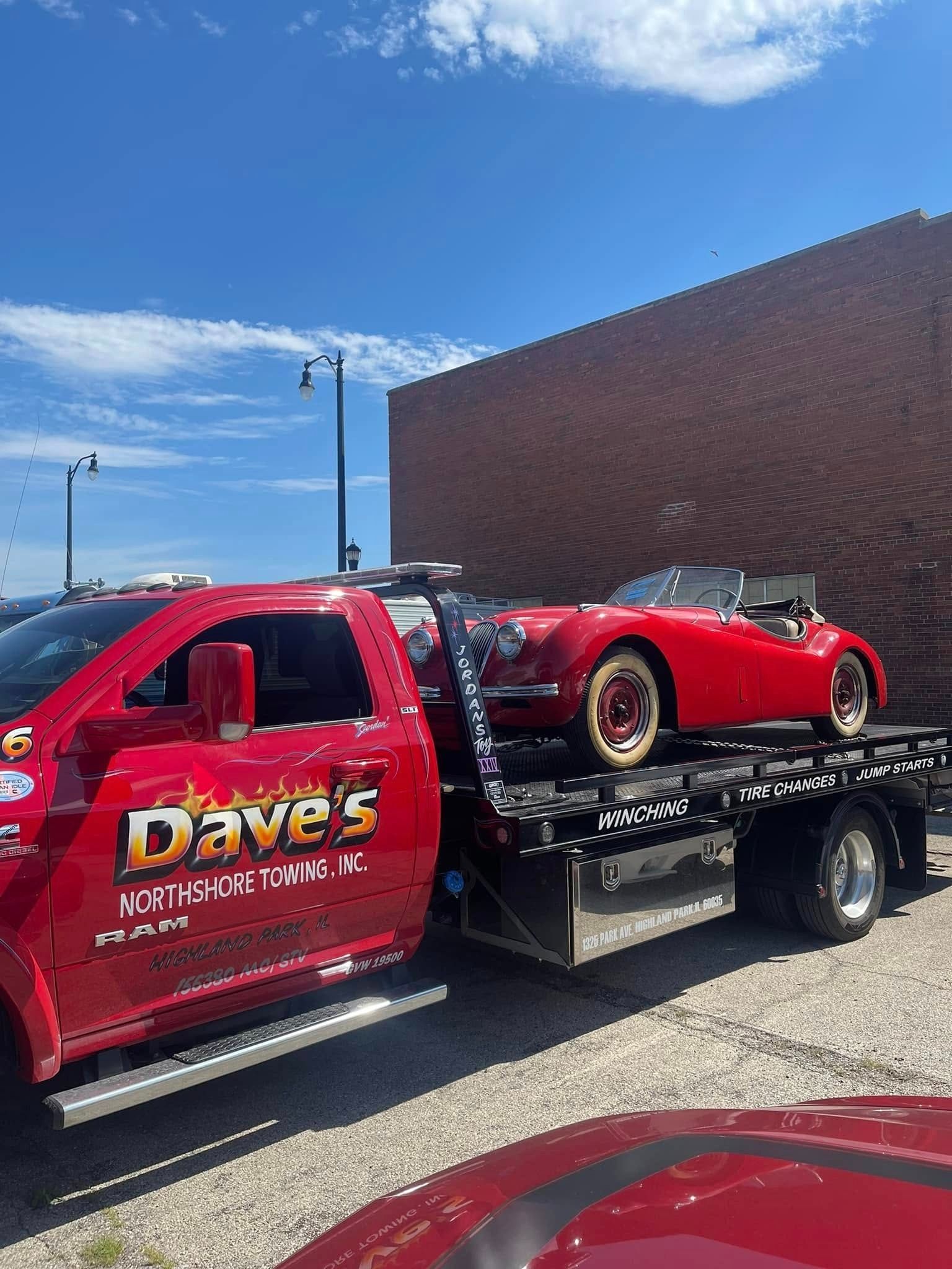 A red tow truck is carrying a red sports car.
