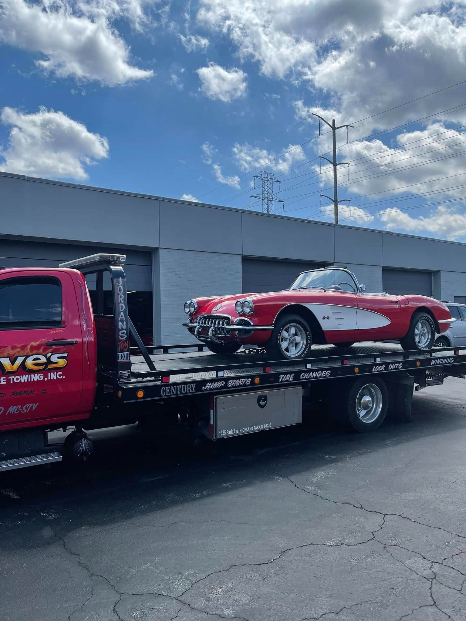 A red car is being towed by a tow truck.