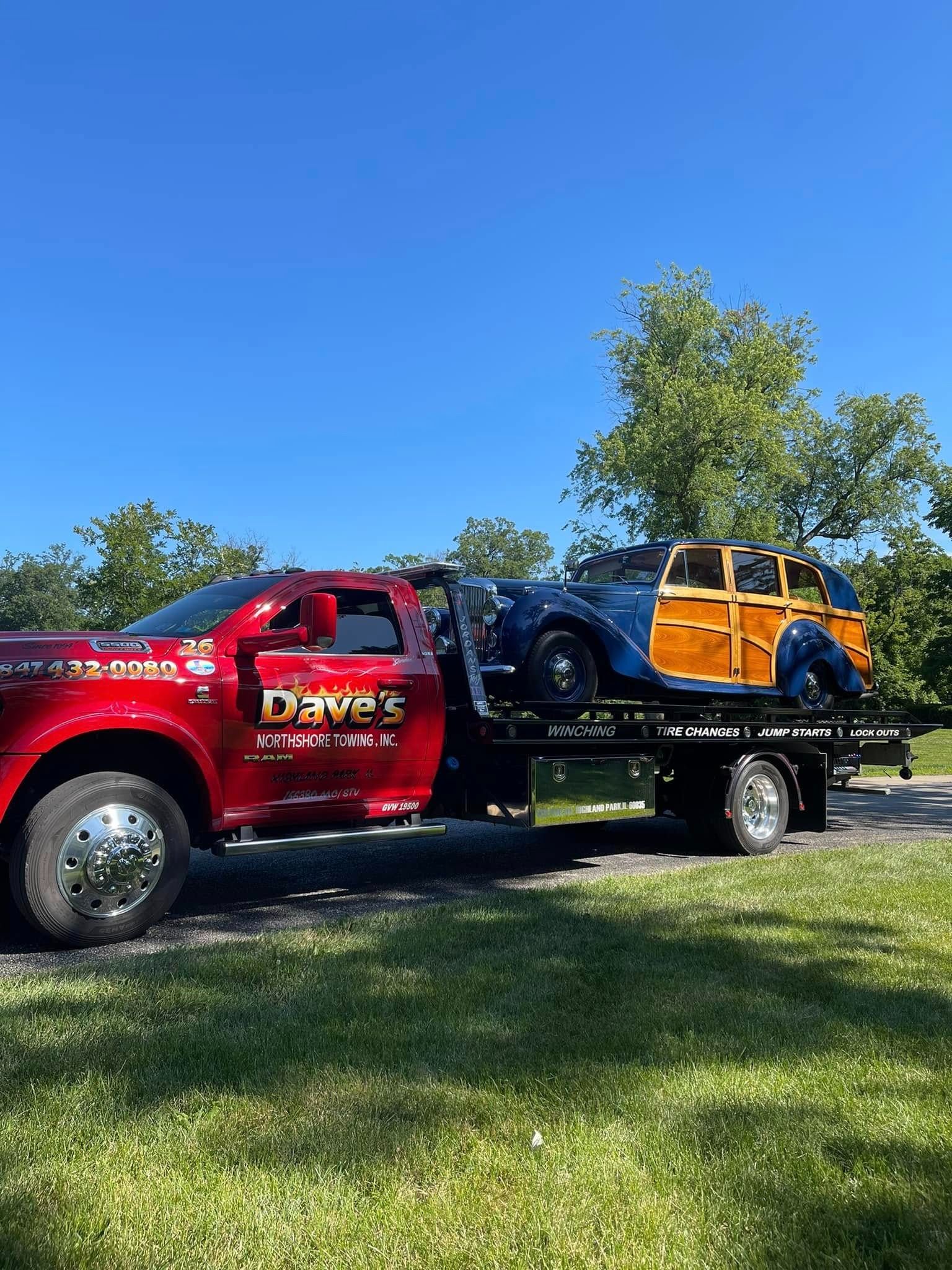 A red tow truck is carrying a yellow car on a trailer.