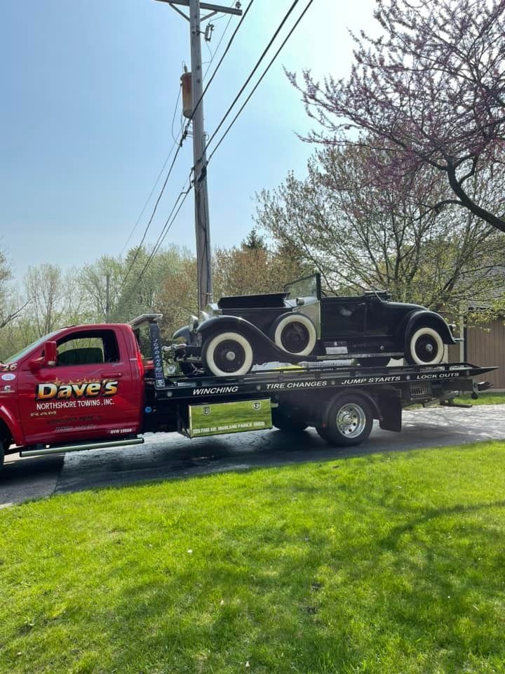 An old car is being towed by a tow truck.