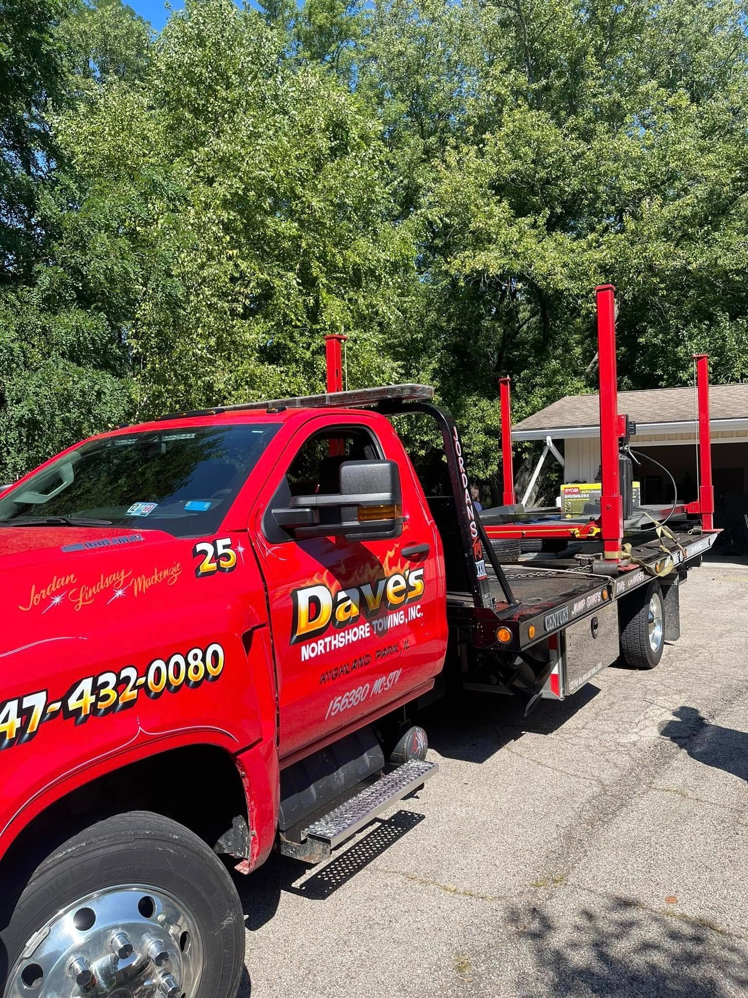 A red tow truck is parked in a gravel lot.