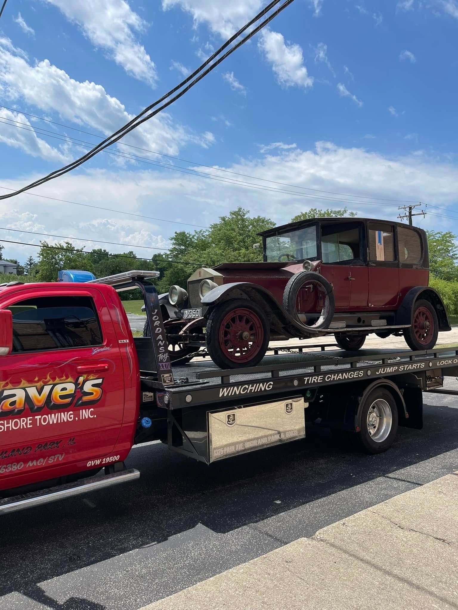 An old car is being towed by a tow truck.