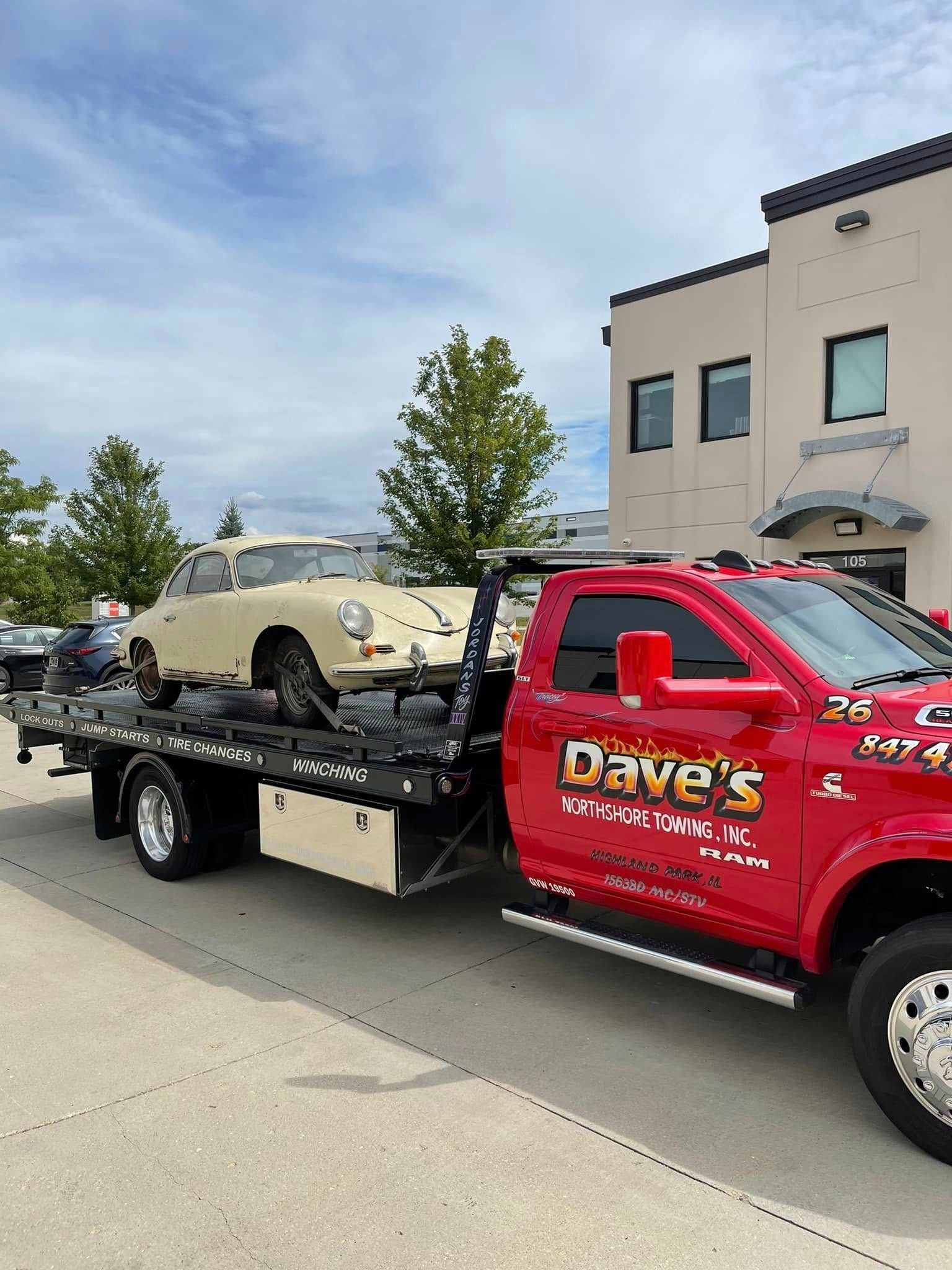 A red tow truck is towing a white car.