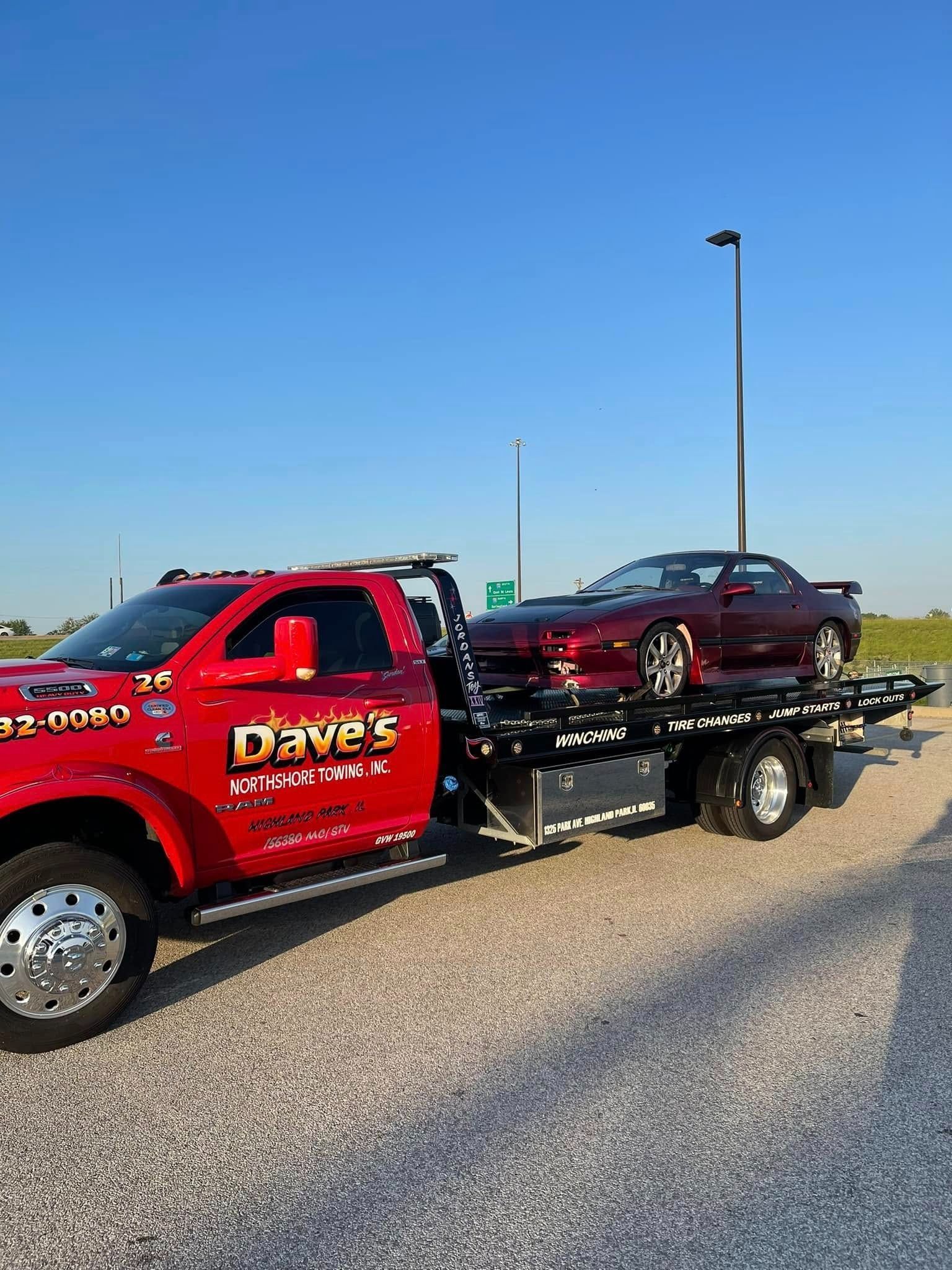 A red tow truck with a red car on the back of it