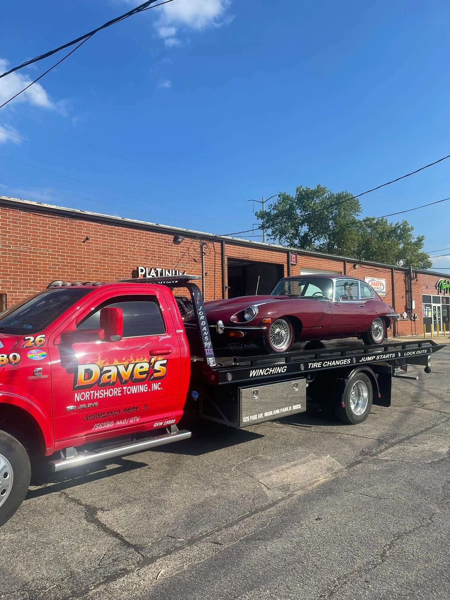 A red tow truck is towing a red car.