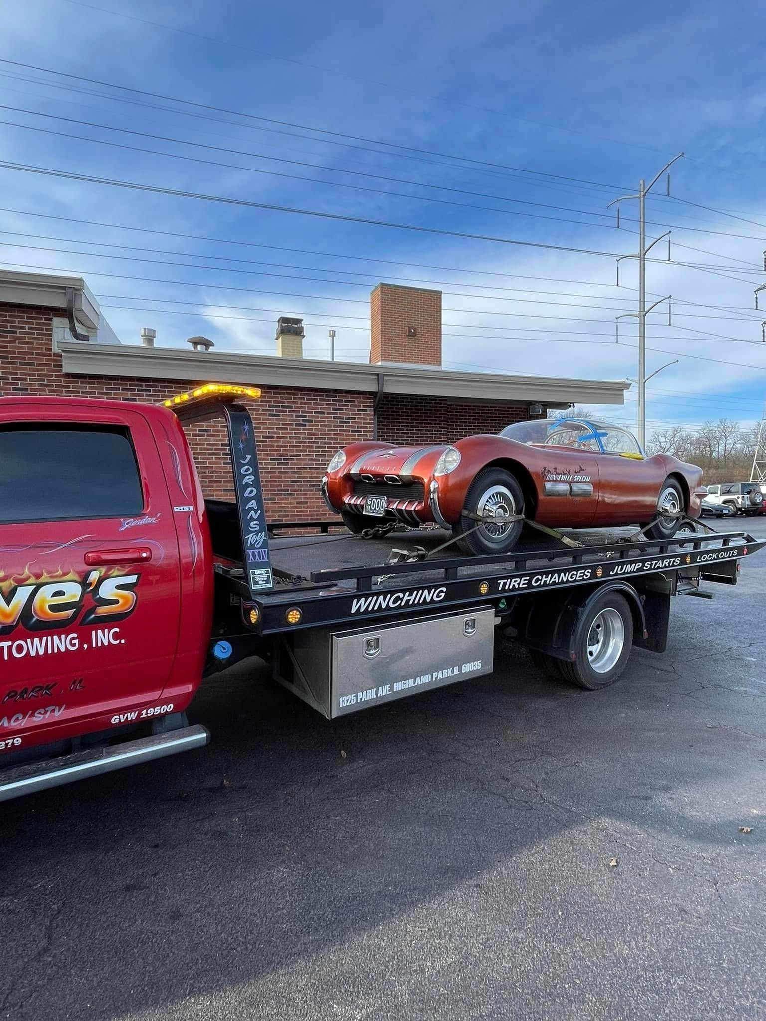 A red tow truck is towing a red sports car.