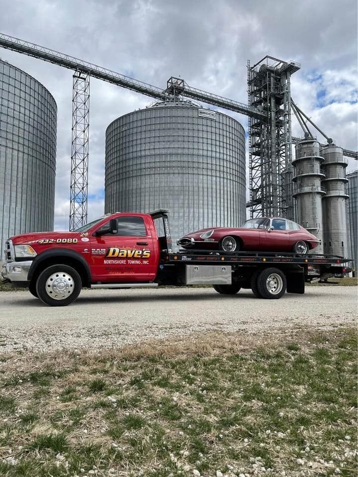A red tow truck is carrying a red car on the back of it.