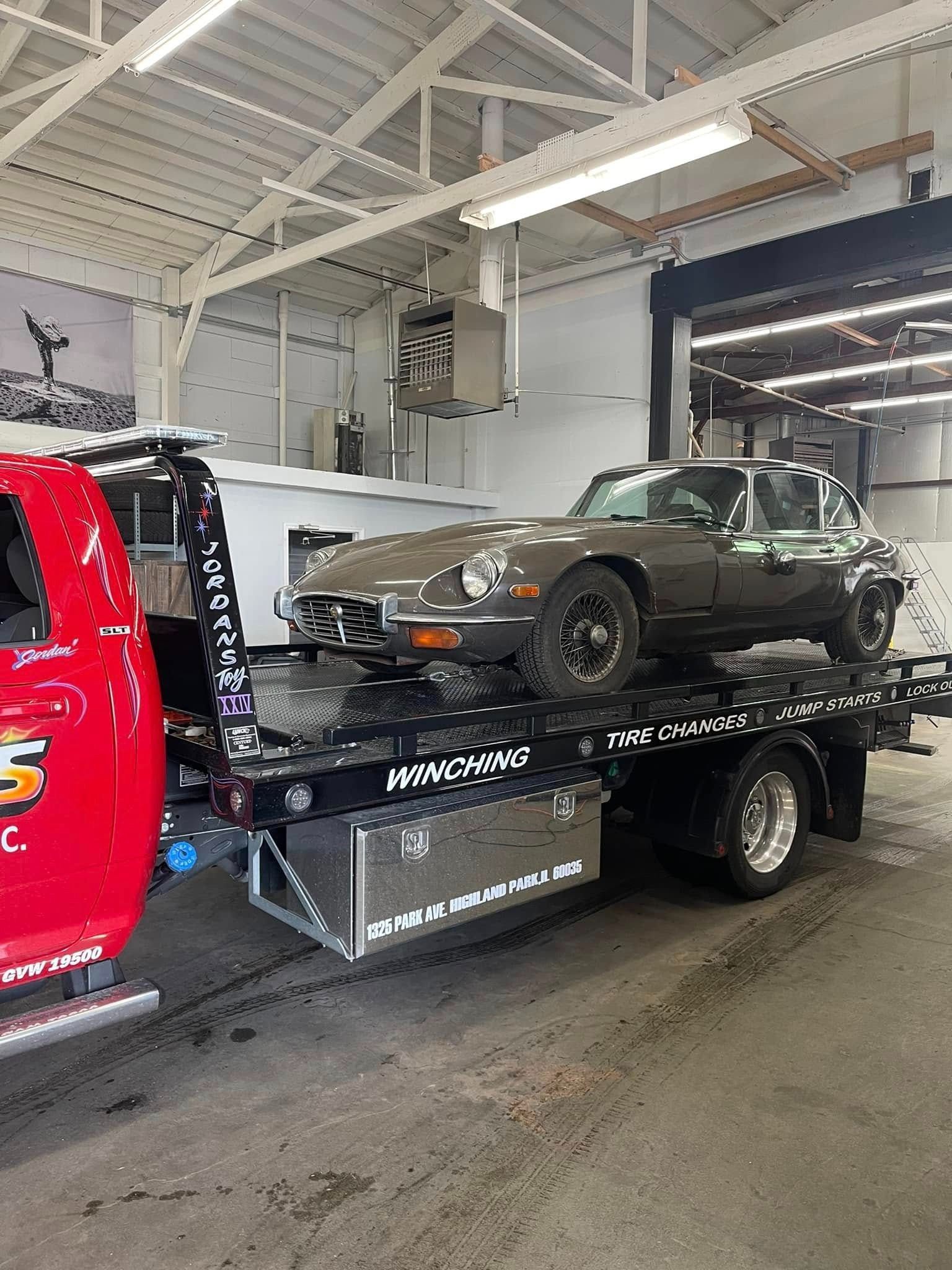 A car is being towed by a tow truck in a garage.