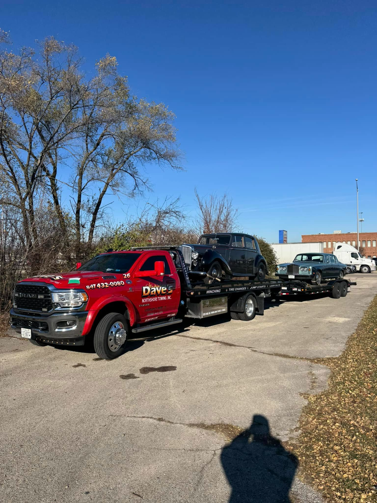 A red tow truck is towing a black truck down a road.