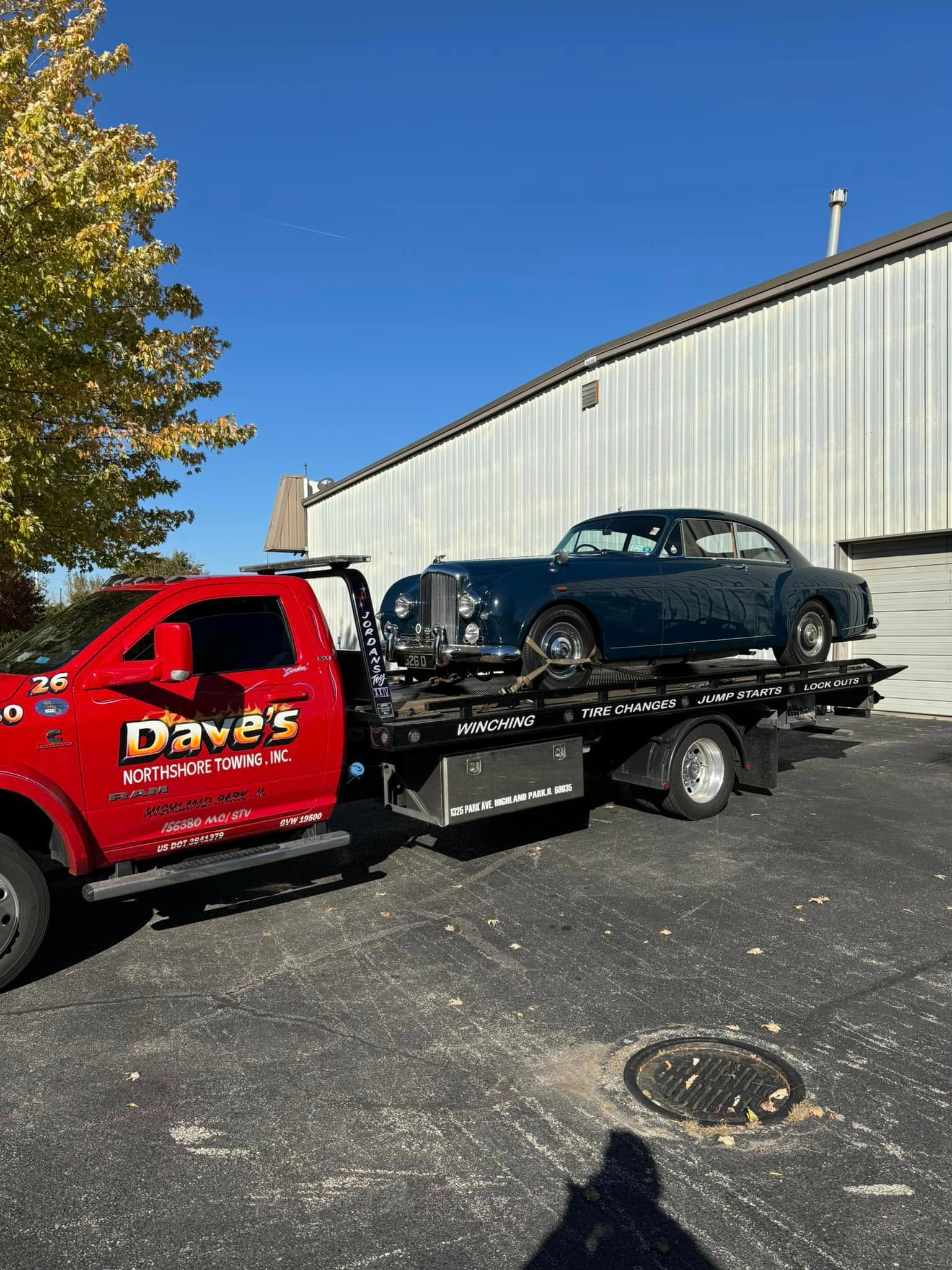 A red tow truck is towing a black car on a trailer.