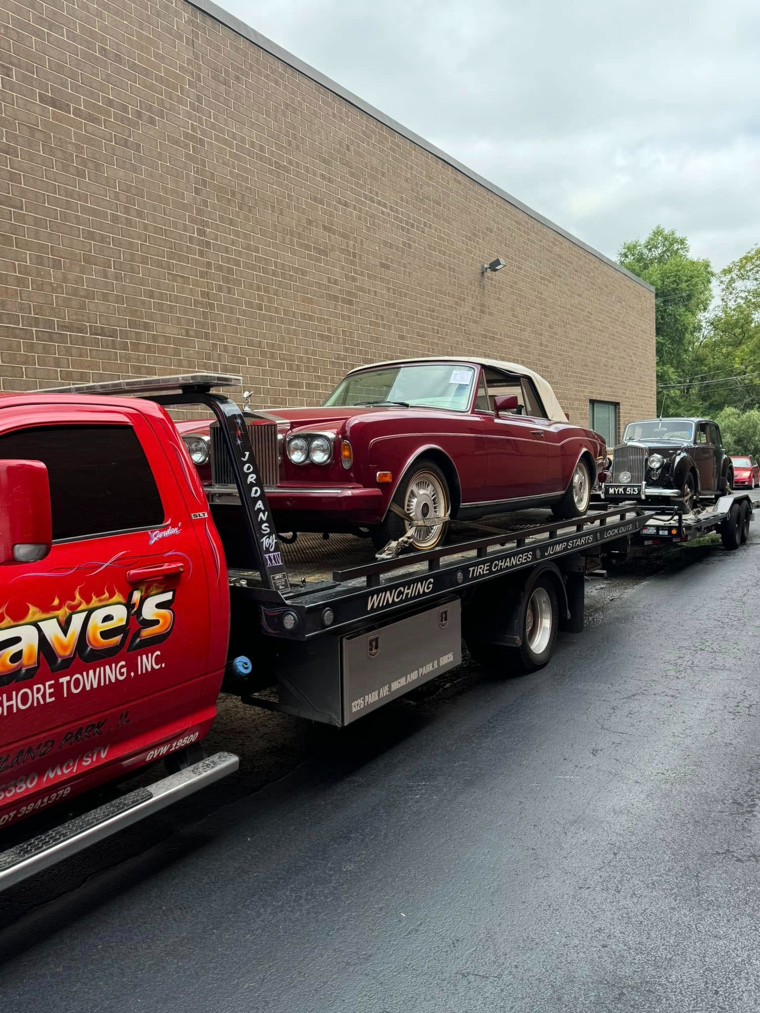 A red car is being towed by a tow truck.
